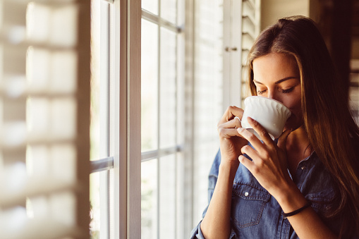 Young woman with coffee cup near the window - Toronto Bangla Town | Digital Bangla Weekly Magazine